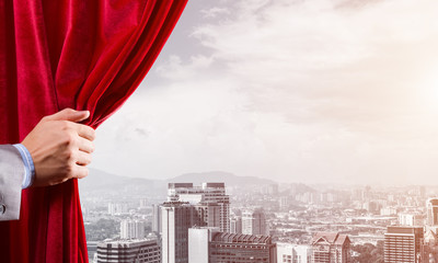 Modern business cityscape behind curtain opened by businessman hand