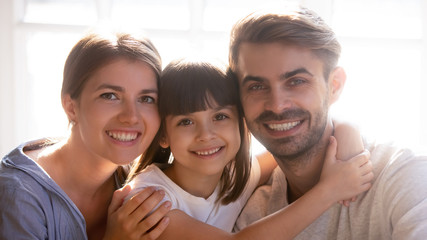 Happy family with little cute daughter smiling looking at camera