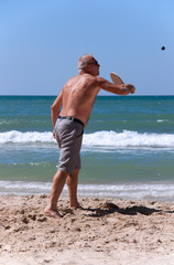 Fototapeta na wymiar handsome grown man playing tennis on the beach