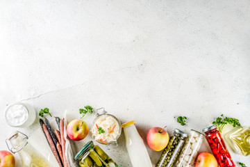 Assortment of various fermented food - apple cider vinegar, fermented meat and vegetables,  sauerkraut, pickled peppers, tomatoes, garlic, capers, white background copy space