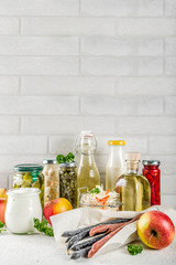 Assortment of various fermented food - apple cider vinegar, fermented meat and vegetables,  sauerkraut, pickled peppers, tomatoes, garlic, capers, white background copy space