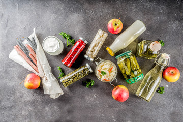 Assortment of various fermented food - apple cider vinegar, fermented meat and vegetables, sauerkraut, pickled peppers, tomatoes, garlic, capers, black background copy space