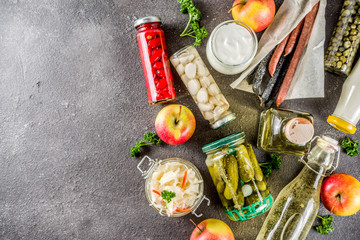 Assortment of various fermented food - apple cider vinegar, fermented meat and vegetables, sauerkraut, pickled peppers, tomatoes, garlic, capers, black background copy space