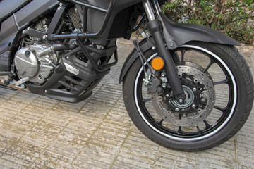 Fototapeta na wymiar Rueda delantera de una moto donde se observa la horquilla y el freno de disco.