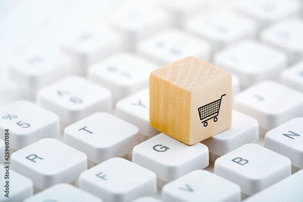 Poster wooden block with shopping cart graphic on computer keyboard. online shopping concept.