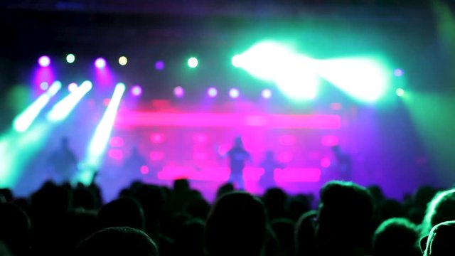 Beautiful lights illuminates the crowd at a rock band performance. Rock band on the stage at a festival.
