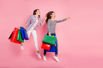 Attention bargains. Profile side full length body size photo of cheerful students stylish consumers have purchases recommend choose advise suggest wear checked shirts jeans isolated pink background 