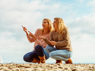 Women on beach having fun pointing