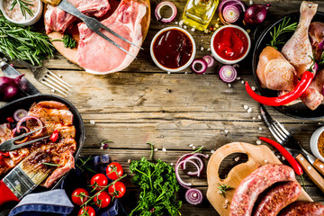 Various raw meat ready for grill and bbq, with vegetables, greens, sauces kitchen grilling...