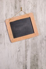 A wooden framed blackboard hanging at an angle on a rustic background with copy space for your text or picture