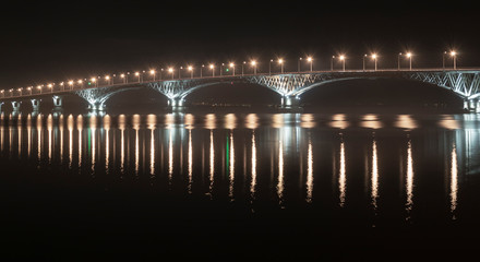 a fragment of an automobile bridge across the Volga River at night lit by lanterns, Saratov Russia