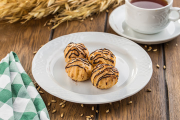 Tasty profiteroles with cream and chocolate glaze on wooden table
