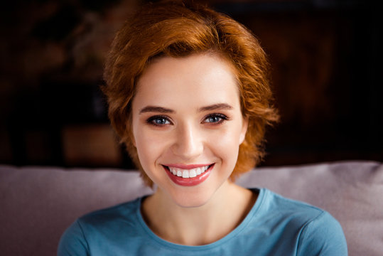 Close up photo beautiful amazing she her lady white teeth red pretty short hairdo imaginary flight thoughtful thought think wear blue pullover clothes sit comfort divan house living room indoors