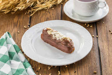 Vanilla Souffle Cake covered with chocolate glaze and decorated with sliced almond on wooden table