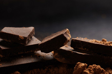 Macro shot of dark chocolate pieces and ccocoa on black background.