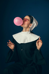 Pure pink devilry. Medieval young woman as a nun in vintage clothing and white mutch sitting on the...