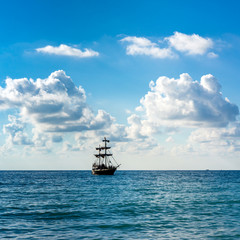 Historic old sailing ship in the sea on the background blue sky and clouds