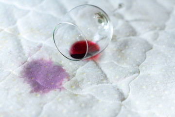 Spilled wine glass on the bed. Accidentally dropped wineglass on white bedsheet. Unlucky,...
