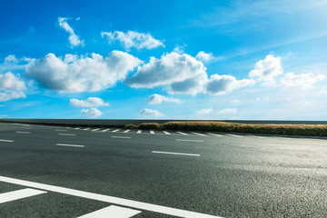 Fototapeta premium Empty asphalt road and blue sky with white clouds scene