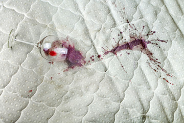 Spilled wine glass on the bed. Accidentally dropped wineglass on white bedsheet. Unlucky,...