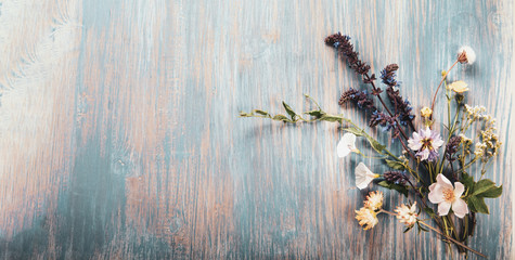 Wild flowers on old grunge wooden background (chamomile lupine dandelions thyme mint bells rape)