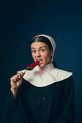 Bite a piece of modernity. Medieval young woman as a nun in vintage clothing and white mutch...