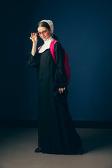 Back to school for new emotions. Medieval young woman as a nun in vintage clothing, red sunglasses...