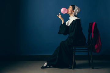 Let's try something new. Medieval young woman as a nun in vintage clothing, white mutch and red bag...