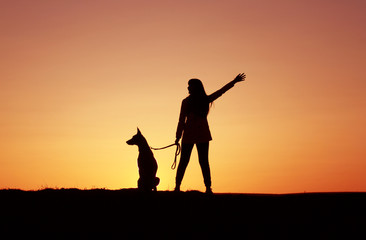 Silhouettes at sunset, girl and dog against the backdrop of an incredible sunset, Belgian Shepherd dog Malinois