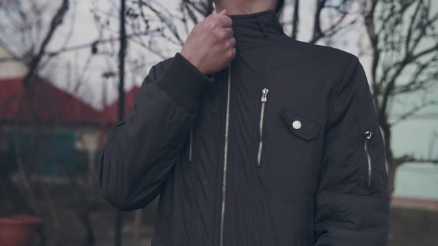 Young man climbing the zipper of his jacket