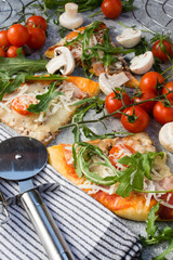 Homemade pizza with rucola and cherry tomatoes.