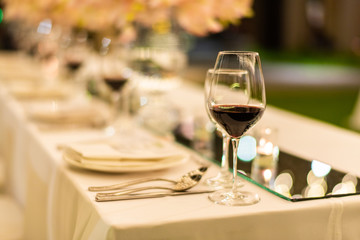 Beautiful wedding table setting decor with glasses of red wine.