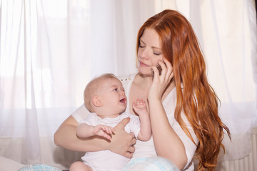 Young mother with baby sits and uses the phone