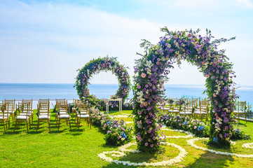 Wedding ceremony. Arch, decorated with flowers on the lawn, beach background, sea in summer. - 259698804