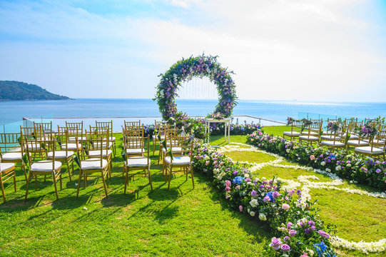 Wedding ceremony. Arch, decorated with flowers on the lawn, beach background, sea in summer.