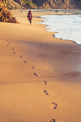 beach, wave and footprints on tropical beach at sunset time