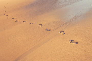 beach, wave and footprints on tropical beach at sunset time