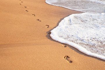 beach, wave and footprints on tropical beach at sunset time