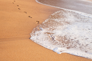 beach, wave and footprints on tropical beach at sunset time