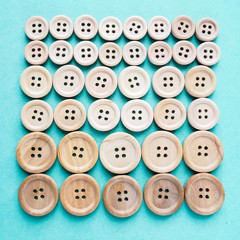 Obraz premium group of large and small beige wooden buttons in row on blue background