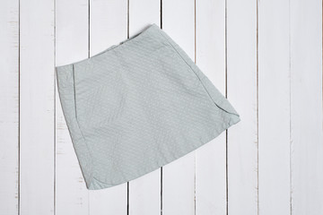 Textured short skirt on white wooden background. Fashion concept.