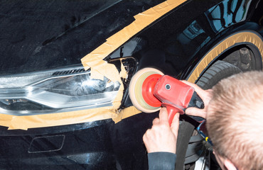 Professioneller Autolackierer poliert ein Fahrzeugteil mit der Poliermaschine - Serie Autowerkstatt - 259702670