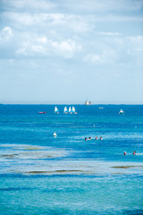 people swimming in the sea in summertime on the isle of Noirmoutier with some boats in the background