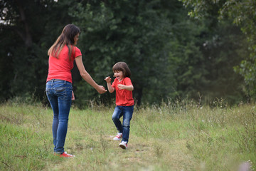 Portrait of Happy mom play with a son in park. Mother and son in red t-shirt playing outside