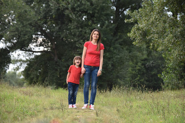 Portrait of Happy mom play with a son in park. Mother and son in red t-shirt playing outside