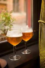 two glasses with Belgian beer on the window