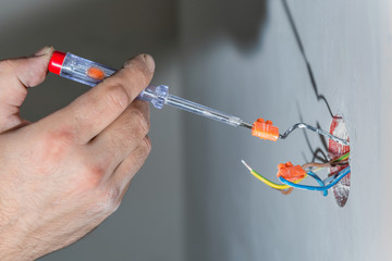 Hands with electrical tester checking the voltage of electrical cables