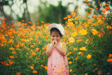 little girl crying in yellow cosmos flower blooming field