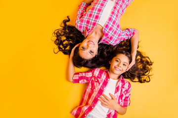 Close up top above high angle view photo beautiful she her models mom daughter funky caress amazing long hair weekend lying floor wear casual pink plaid checkered shirts isolated yellow background