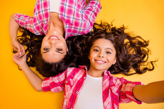 Close up top above high angle view photo beautiful she her models mom daughter caress weekend make take funky selfies lying floor wear casual pink plaid checkered shirts isolated yellow background